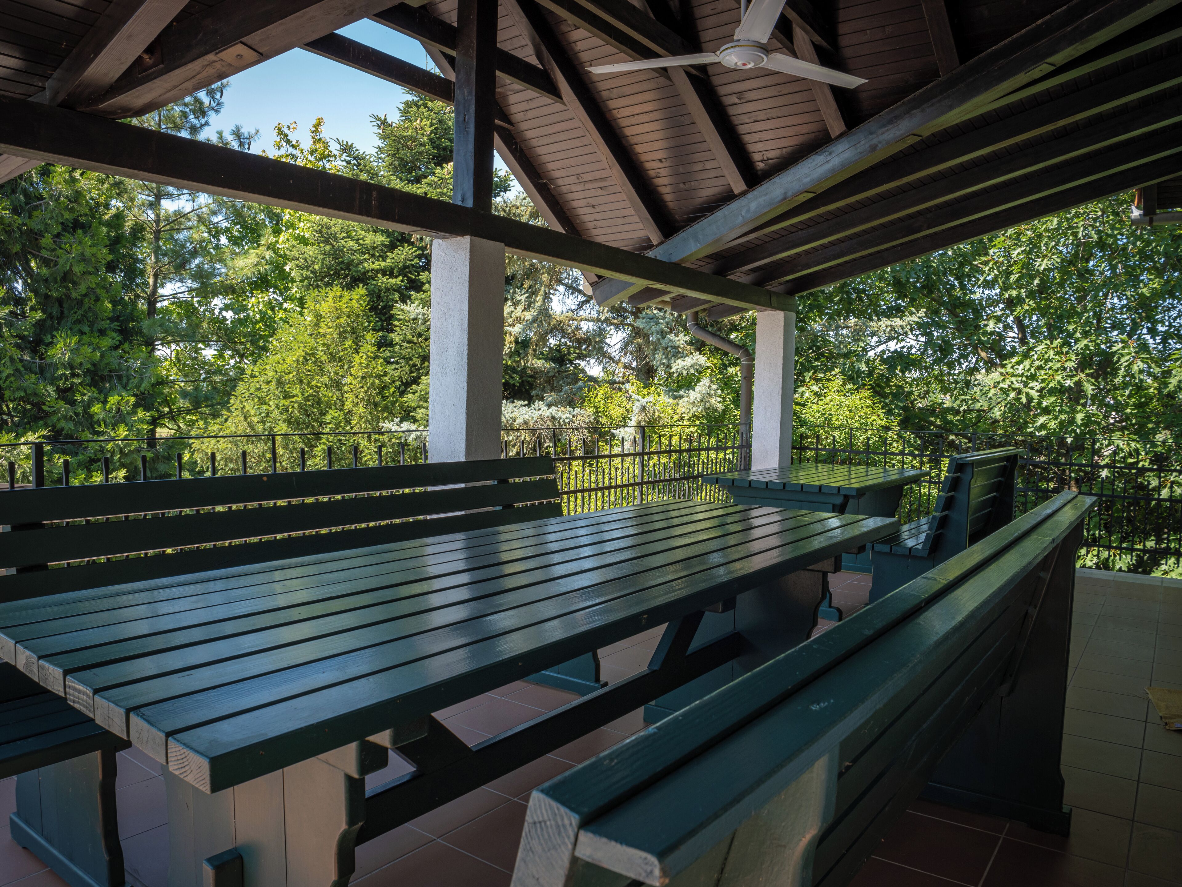 A covered picnic area with benches and a ceiling fan.