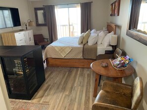 Een hotelkamer met een bed, een klein tafeltje met een mandje, een televisie, een kast en een raam met gordijnen.