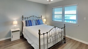 A bedroom with a bed, a ceiling fan, a window with blinds, and a nightstand with a lamp. - Ocean Echo #303 (Gulf Shores)