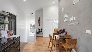 Una cocina moderna con comedor, una pared blanca con el texto 'the shiloh house' y una mesa de comedor de madera con sillas.