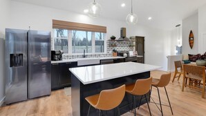 Una cocina moderna con una isla central, electrodomésticos de acero inoxidable e iluminación colgante.
