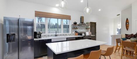 A modern kitchen with a central island, stainless steel appliances, and pendant lighting.