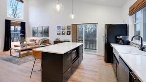 Una cocina moderna con una isla grande, armarios negros e iluminación colgante.