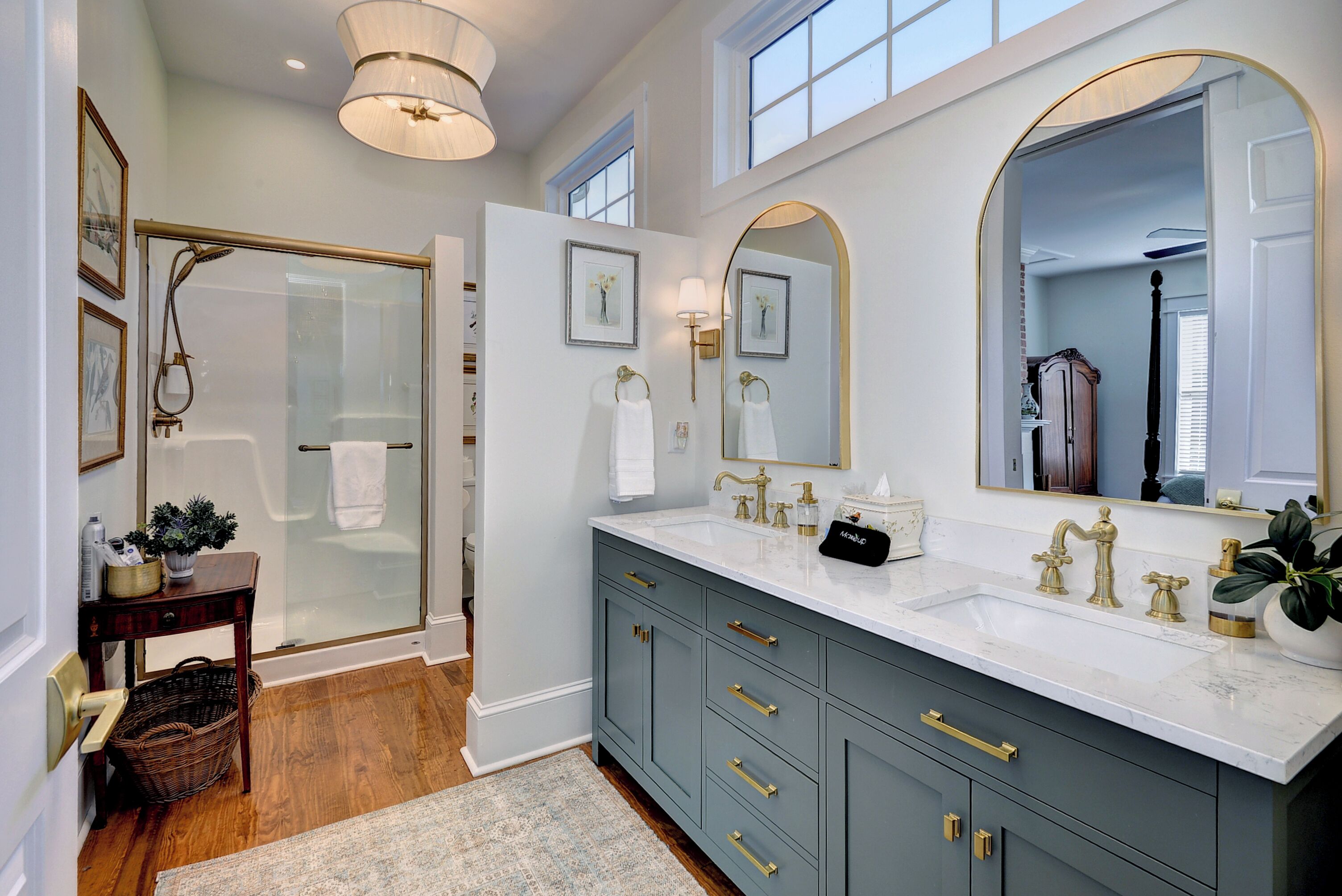 A bathroom with a large mirror, a shower, and a vanity with a sink and towel rack.