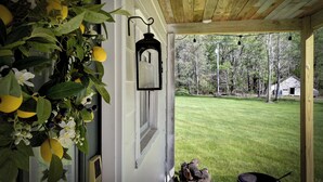A porch with a wooden ceiling, a hanging lantern, and a view of a grassy yard.