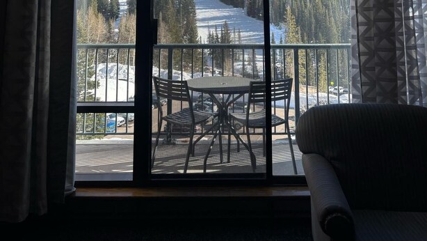Ein Zimmer mit großem Fenster und Blick auf eine verschneite Berglandschaft.