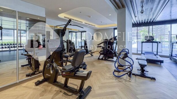 Ett modernt gym med olika typer av träningsutrustning, stora fönster och en ren och rymlig inredning.