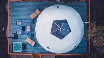 Luchtbeeld van een dakzwembad met een grote witte koepelstructuur, ligbedden, een jacuzzi en een betegeld zonnedek.