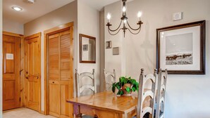 A dining area with a wooden table, chairs, a chandelier, and a framed picture on the wall. - Studio Condo w/ Fireplace & Pool | Near Gondola! (Keystone)