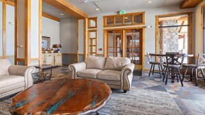 A lobby with a beige sofa, wooden coffee table, and a stone wall. - Studio Condo w/ Fireplace & Pool | Near Gondola! (Keystone)