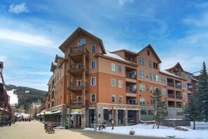 A multi-story hotel with balconies, a ski slope in the background, and a snowy ground. - Studio Condo w/ Fireplace & Pool | Near Gondola! (Keystone)