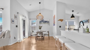 Un'ampia cucina con zona pranzo, pavimento in legno e lampade a sospensione.