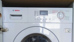 Una lavadora Bosch de carga frontal con pantalla digital, panel de control y varias opciones de lavado.