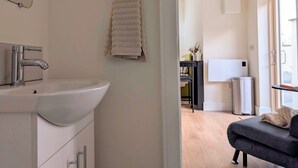 Un baño moderno con lavamanos, espejo y toallero.