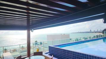 Una piscina en la azotea con vistas al océano y al horizonte urbano.