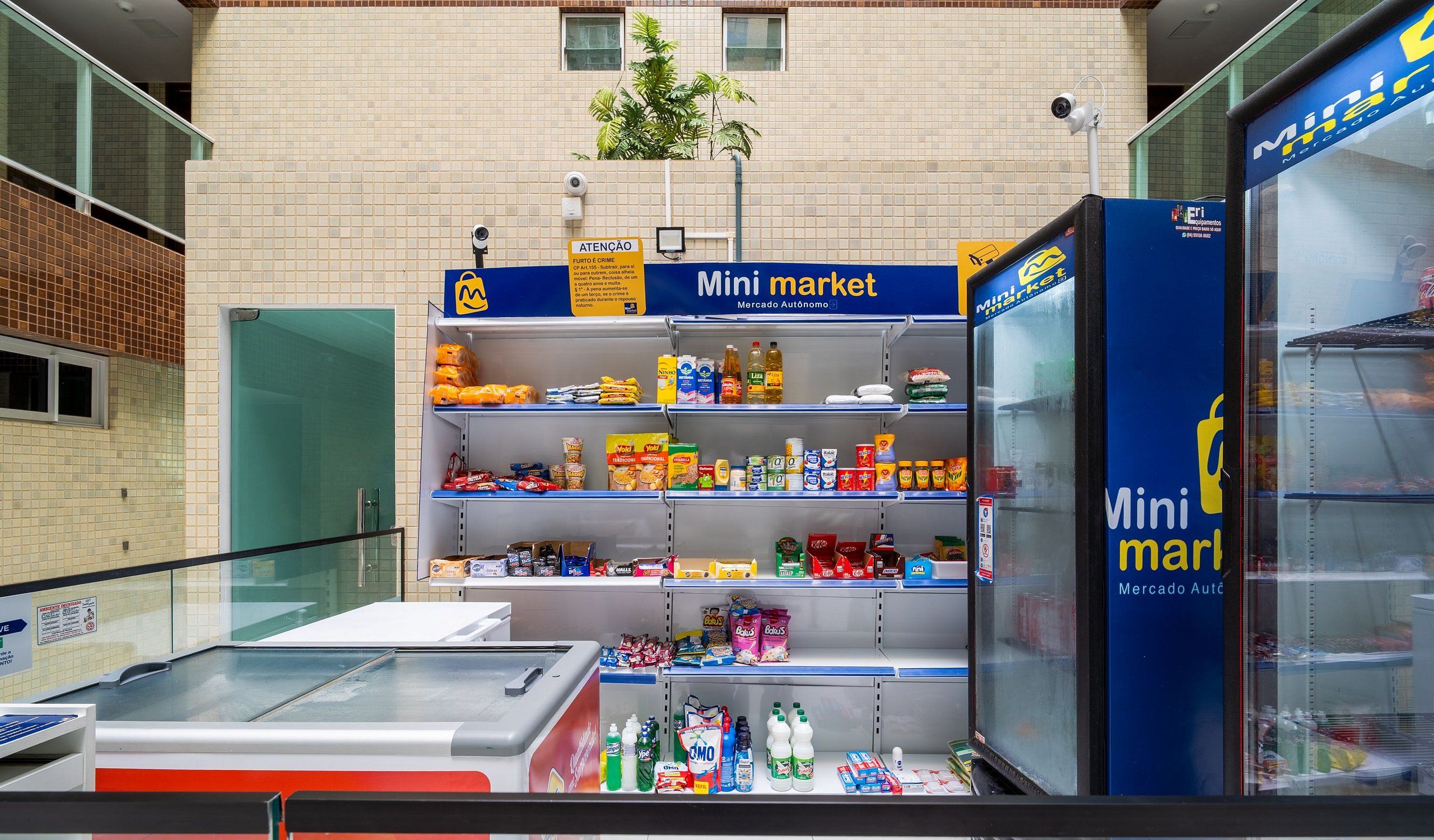 Un quiosco de mercado pequeño con estantes llenos de diversos productos alimenticios y un refrigerador.