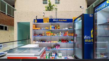 Un quiosco de mercado pequeño con estantes llenos de diversos productos alimenticios y un refrigerador.