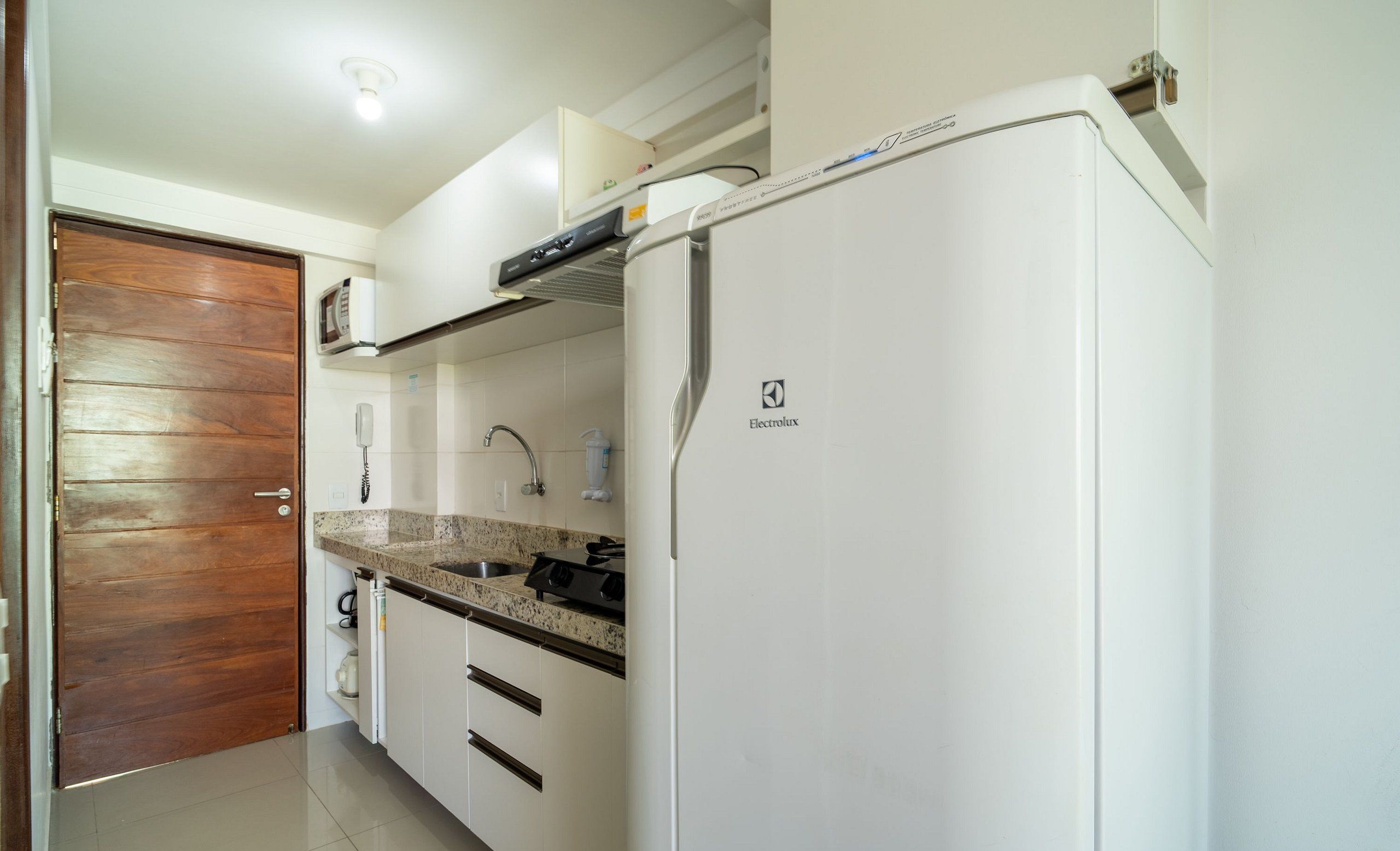 Una cocina con armarios blancos, encimera de granito, microondas y refrigerador con el logotipo de Electrolux.