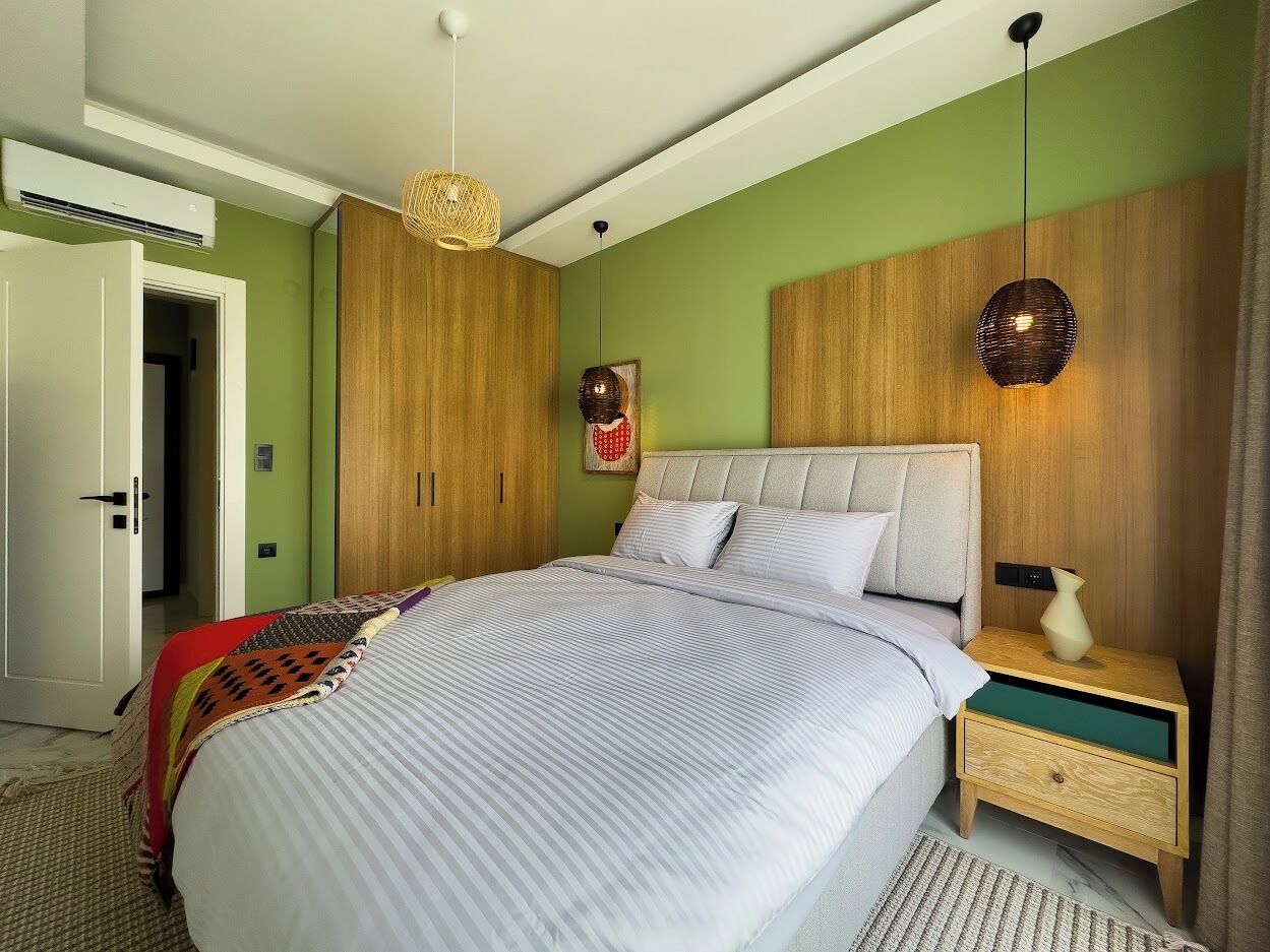 A bedroom with a bed, bedside tables, a wardrobe, and a hanging light fixture.