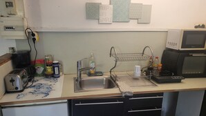 Una cocina con un lavamanos, microondas, tostadora y refrigerador.