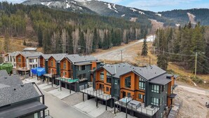 A row of modern multi-story buildings with a view of a mountainous landscape. - Chalet Grande Ourse | Slope-Side | Private Hot Tub (Panorama)