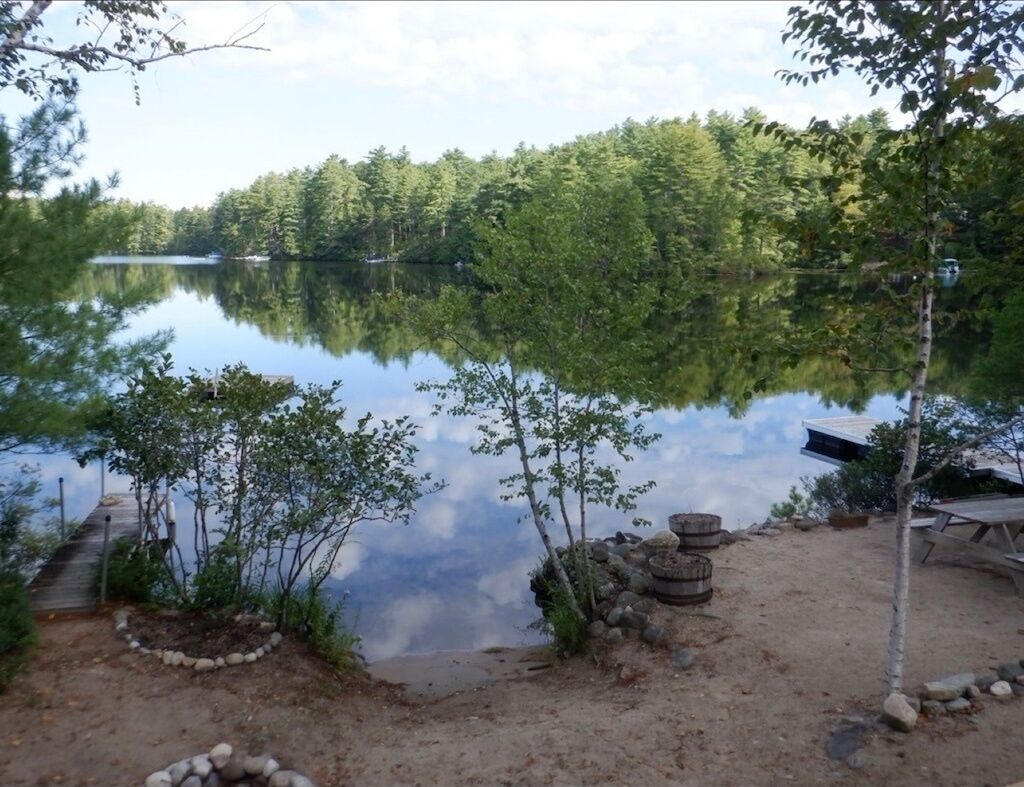 Un terrain de camping au bord du lac, équipé d’une jetée, d’une table de pique-nique et d’une petite construction en pierre.