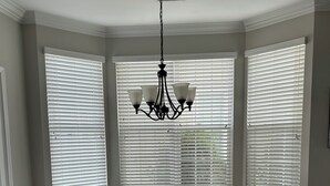 A dining room with a large table and six chairs, large windows with blinds, and a chandelier. - Pond View near Old Town Bluffton (Bluffton)