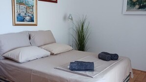 A neatly made bed with a beige bedspread, pillows, and a folded towel. - Apartmani Green Oasis - One Bedroom Apartment with Terrace and Sea View (Vis)
