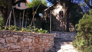 A stone pathway leading to a rustic building with a stone wall and greenery. - Apartmani Green Oasis - One Bedroom Apartment with Terrace and Sea View (Vis)