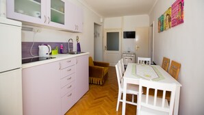 Una cocina compacta con zona de comedor, suelo de madera y una pequeña mesa con sillas.