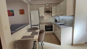 Una cocina compacta con comedor, horno empotrado y pileta.