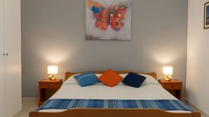 Una camera da letto con un letto di legno, due comodini con lampade e un quadro astratto dai colori vivaci appeso al muro.