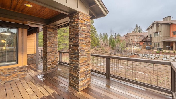 A wooden deck with stone pillars, a glass door, and a view of neighboring buildings. - 4 BR / 3.5 BA Home Near Downtown Truckee & Skiing! (Truckee)