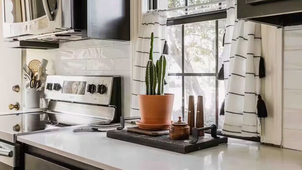 A modern kitchen with a white countertop, a stove, and a window with curtains. - Cozy Historical Home, Walk to Downtown Edmond (Edmond)