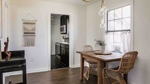 A dining area with a wooden table, wicker chairs, a vase with plants, and a hanging light fixture. - Cozy Historical Home, Walk to Downtown Edmond (Edmond)