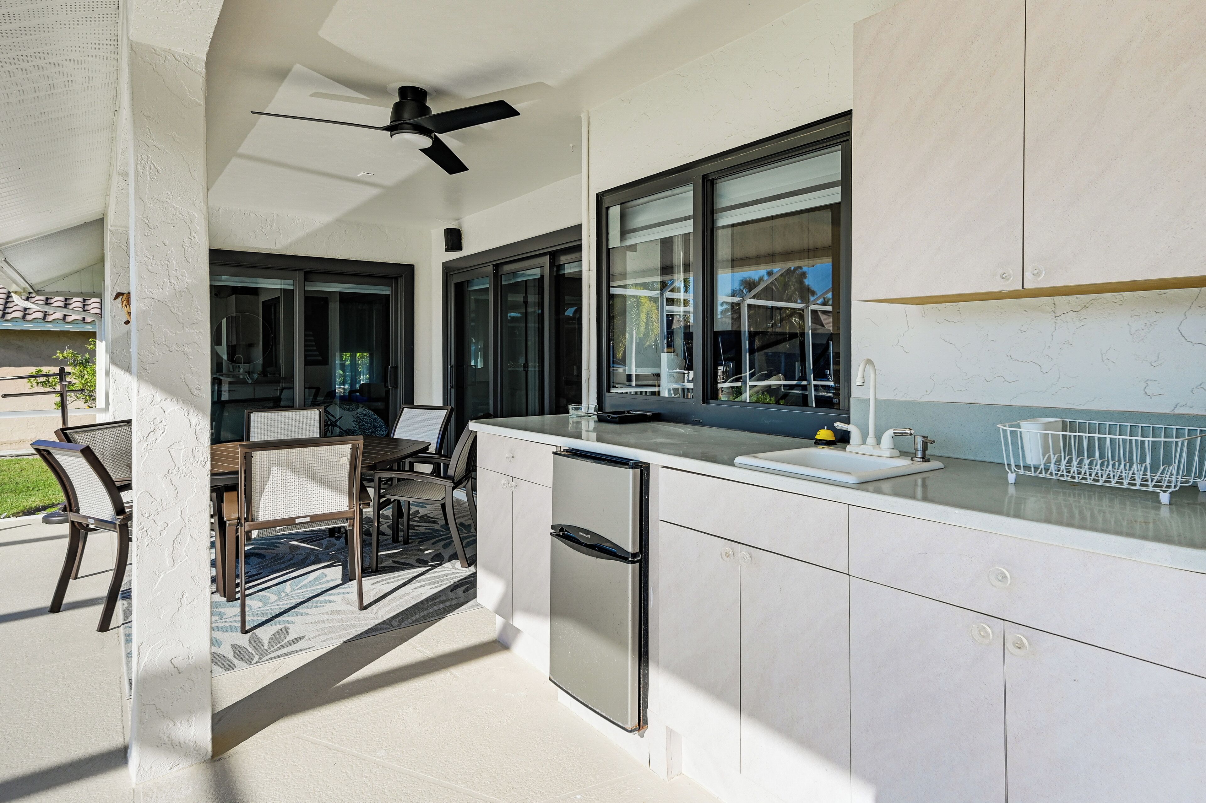 Una cocina moderna con refrigerador empotrado, un lavamanos y un ventanal con vista al jardín trasero.
