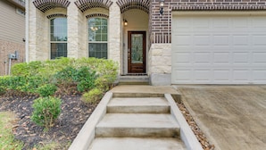 A two-story house with a front entrance, a garage, and a landscaped front yard. - Lake Conroe Home w/ Resort-Style Perks & Patio (Montgomery)