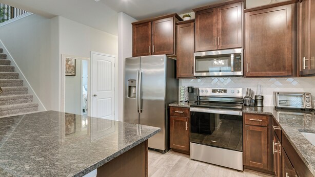 A modern kitchen with granite countertops, stainless steel appliances, and wooden cabinets. - Lake Conroe Home w/ Resort-Style Perks & Patio (Montgomery)