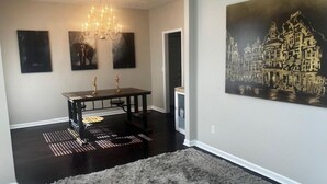 A dining area with a dark wooden table, three paintings on the wall, and a chandelier. - Sleek Chateau Residence: 4BR Modern Hideaway in Jonesboro (Jonesboro)