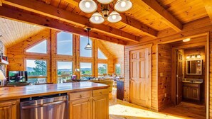 A spacious wooden cabin with a large kitchen area, multiple windows, and a built-in dishwasher.