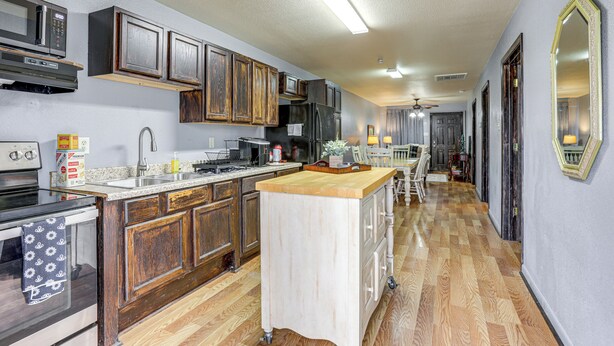 A kitchen with wooden cabinets, a central island, and a microwave. - Near Universities & LR: Family Apt in McRae, Ark (McRae)