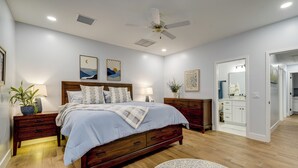 Een slaapkamer met een houten bed, nachtkastjes, een plafondventilator en kunstwerken aan de muur.