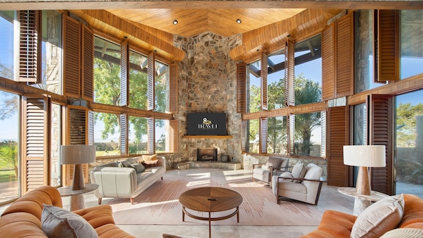A spacious living area with a stone fireplace, large windows, and modern furniture.