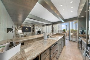 A modern kitchen with granite countertops, a stone backsplash, and a large island. - Iconic Hilltop Estate|270° Views on Piestewa Peak (Phoenix)