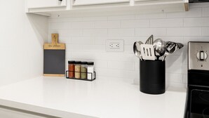 Una cocina con armarios blancos, un especiero negro y un portalápices negro.