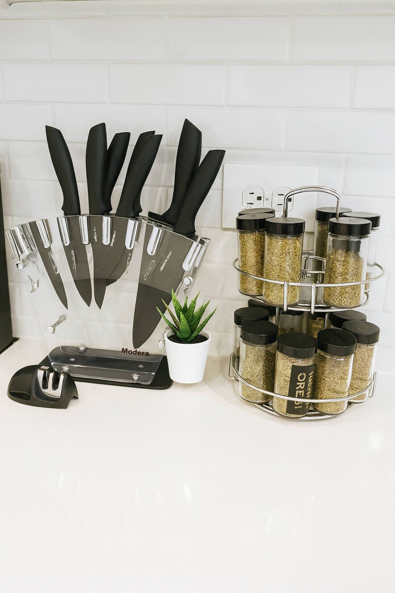 A kitchen counter with a knife block, a spice rack, and a small potted plant.