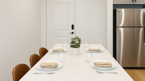 A modern kitchen with a white island, stainless steel refrigerator, and brown leather chairs. - WorkerFriendly,Wash/Dry,WiFi, Pool,A+Location,Gym (Sherman)