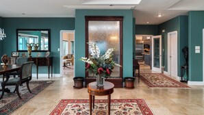 A spacious living room with a large window, a dining area with a table and chairs, and a hallway leading to other rooms.