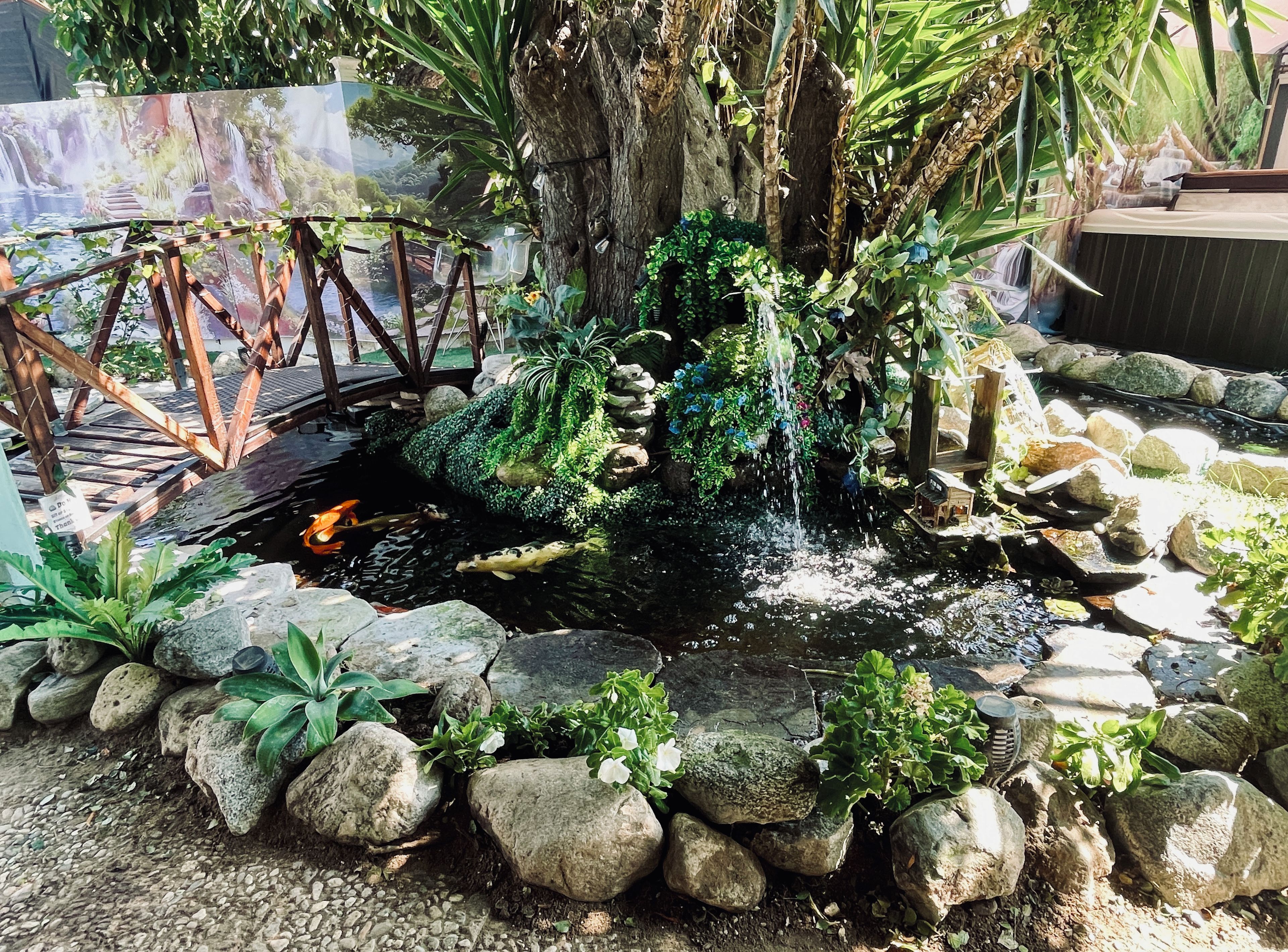 A koi pond with a bridge, surrounded by rocks and plants.