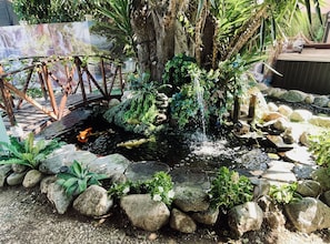 A koi pond with a bridge, surrounded by rocks and plants.